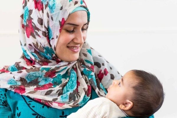 ASP – EMERGENCY CAMPAIGN 600X400 A woman wearing a brightly coloured headscarf looks lovingly at the child she is holding.