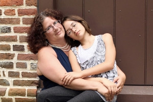 A mother holds her daughter on the front step of their home