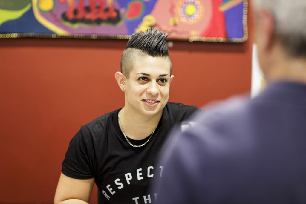 Woman with a mowhawk smiling and talking to a man