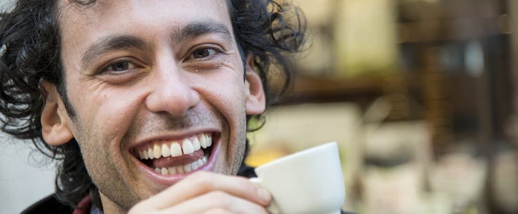 man smiling while drinking espresso