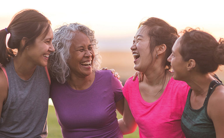 Four ethnic women laughing together after an outdoor workout